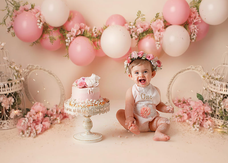 Bebé de 1 año en un estudio fotográfico con un pastel y globos